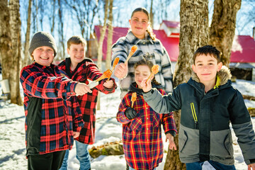 Photo showing children tasting maple syrup with wooden spoon - 777683425