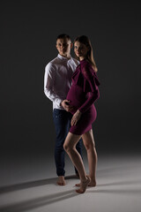 two people, portrait of a pregnant couple on a black background, pregnant couple standing