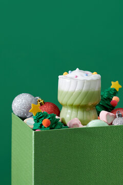 A glass of iced tea stands in a green colored box, next to toys