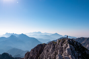 Hiker man standing on mountain top Vertatscha with panoramic view of Koschuta mountain range seen...