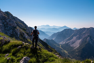 Fototapeta na wymiar Hiker man with scenic view of mountain peak Grintovec, majestic Kamnik-Savinja Alps, Slovenia, Europe. Magnificent hiking trail in untamed Karawanks, Austrian border. Magical mountains Slovenian Alps