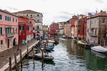 Fototapeta na wymiar Scenic view of peaceful canal Vena nestled in charming town of Chioggia, Venetian Lagoon, Veneto, Italy. Small boats floating in calm water. Enchanting reflections create atmosphere of tranquility