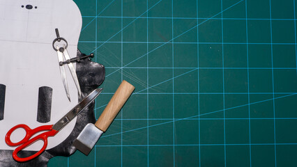 Work table. Designing a leather bag, with scissors, thread, compasses and cutter. 