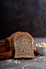 Sliced whole grain loaf bread on dark rustic wooden background
