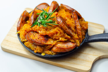 Traditional Polish dish called bigos made of sauerkraut, sausage and mushrooms, food served warm in a cast iron pan - 777690656