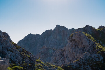 Scenic view of majestic mountain summit cross of Vertatscha (Vrtaca) in untamed Karawanks, border Slovenia Austria. Hiking trail along steep rock cliffs and wilderness of Slovenian Alps in summer