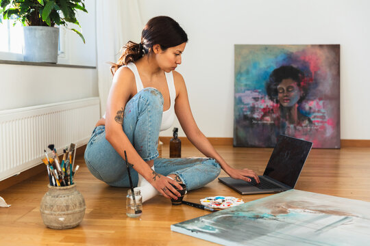 Young woman painting canvas at home
