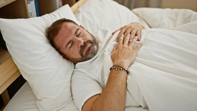 A middle-aged man with a beard and grey hair sleeps peacefully in a cozy bedroom, exemplifying relaxation and comfort.