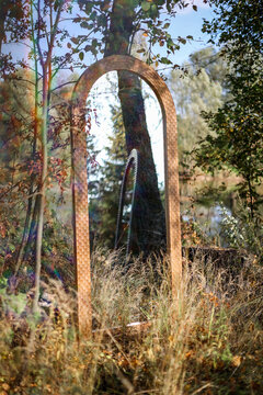 Handmade wooden frame mirror reflecting another mirror in the forest