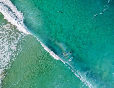 Top down view of surfers in beautiful clear waters with rainbow