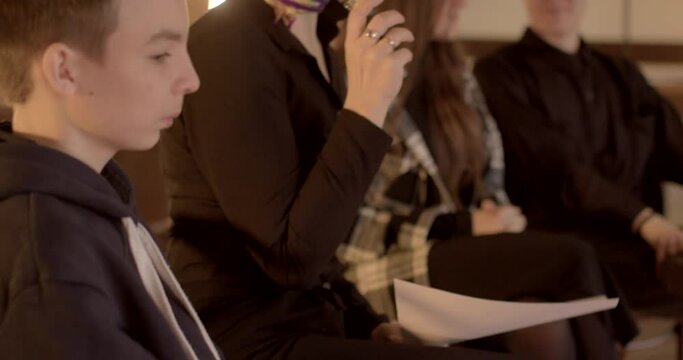 Teacher hands microphone to student to express their rights. School parliament session where students engage in discussions and debates, voicing their opinions on school matters. Woman and teenagers.