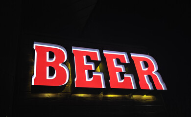 Glowing red Beer sign at entrance to pub at night - 777701474