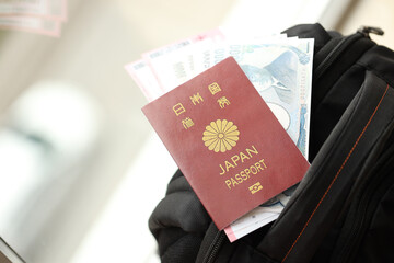 Fototapeta premium Japan passport with japanese yen money bills with airline tickets on backpack close up