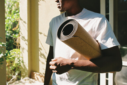 A man with a yoga mat outside the house