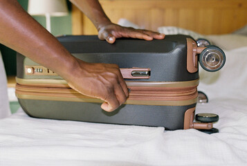 A man zipping up the suitcase