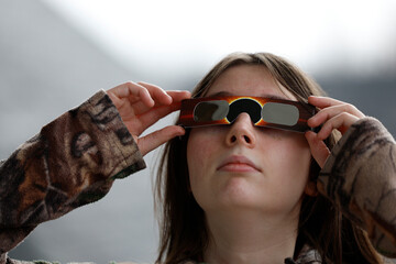Une jeune adolescent regarde l'éclipse solaire avec des lunettes de protection