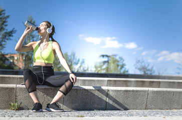 healthy woman resting and listening music with mobile phone while doing yoga and workout