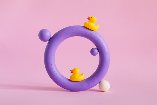Violet colored torus with rubber ducks on pink paper background