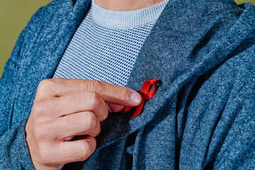 man pinning a red ribbon in his lapel