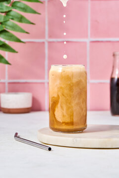 Iced latte on pink tile backdrop