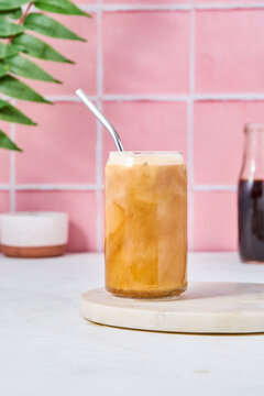 Iced latte on pink tile backdrop
