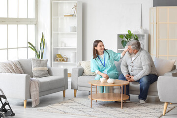 Mature man with nurse sitting on sofa at home