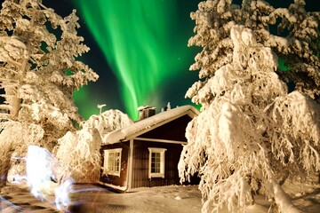 Green northern light behind a mountain lodge in Finland 