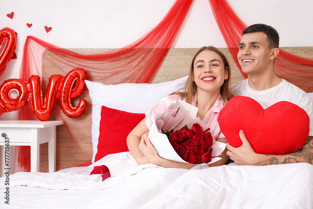 Sticker Young couple with roses and heart-shaped pillow in bedroom on Valentine's Day