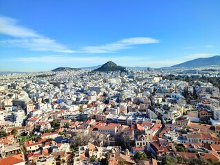 A panoramic view of Athens, Greece from the top of the Acropolis hill. Mount Lycabettus can be seen in the center of the picture. The Anafiotika neighborhood is located at the bottom of the photo.