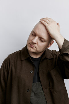 balding man holding his head to prevent it from showing
