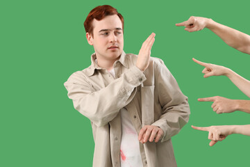 People pointing at young man on green background. Accusation concept