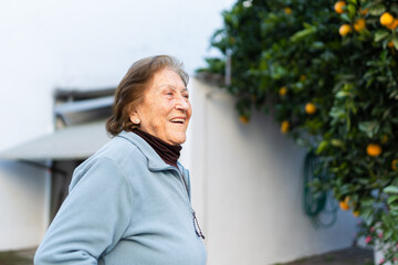 Portrait of a happy senior woman with oranges in the garden.