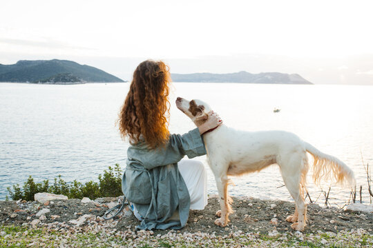 Woman with her dog near the sea on the sunset 