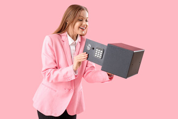 Beautiful young happy woman with safe box on pink background