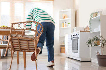 Man tripping over chair in kitchen