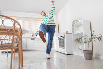 Young man falling after slipping on banana peel in kitchen