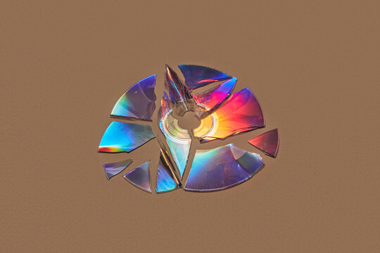 Damaged CD disc with holographic surface over brown background