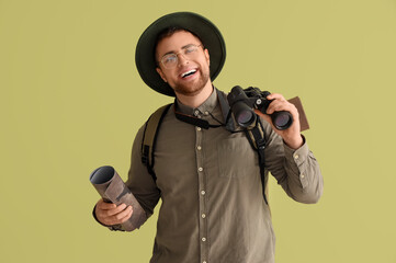 Young male tourist with binoculars on green background