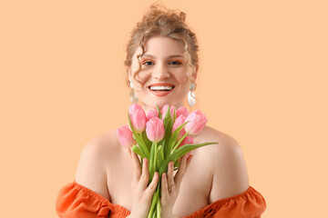 Pretty young woman with bouquet of beautiful pink tulips on yellow background