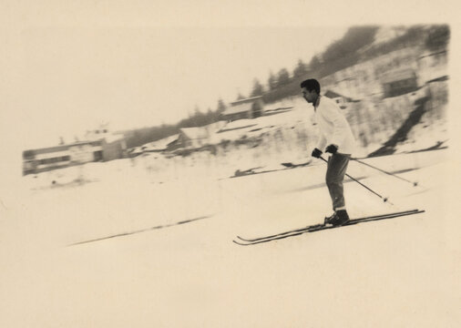 1957.  Skier descends down a snowy slope.