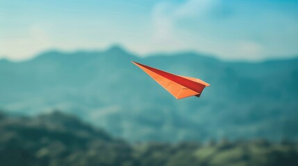 A bright red paper airplane flies high above the mountains. Symbolizes dream, freedom, adventure and independence.