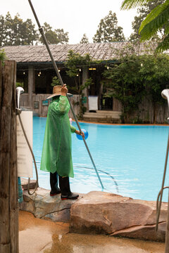 Person cleaning a swimming pool.
