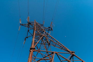 View of the majestic electrical pylon. Power line support against a blue sky.