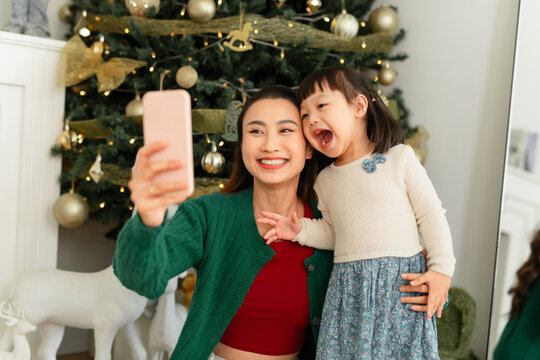 Happy Asian mother and daughter taking selfie on smartphone