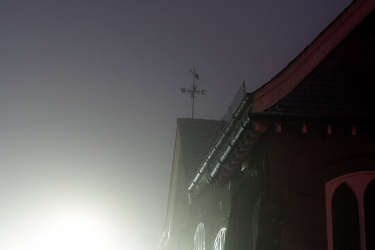 A weather vane on top of a building at night