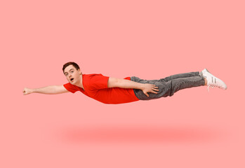Surprised young man flying on pink background © Pixel-Shot