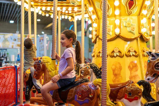 Happy Little Girl and Boy Riding a Carousel Horse.