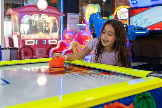Energetic Play. Young Girl Enjoy Air Hockey Thrills at the Arcade Park