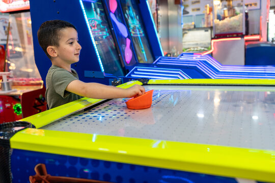 Energetic Play. Little Child Enjoy Air Hockey Thrills at Arcade Park.