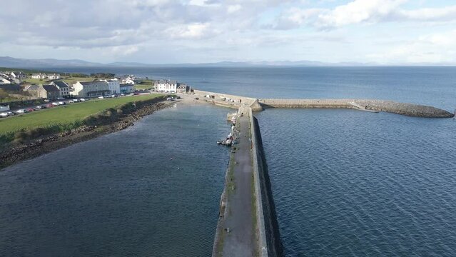 A drone shot moving along the pier at a seaside village along the Atlantic Ocean. Mullaghmore, Co. Sligo, Ireland